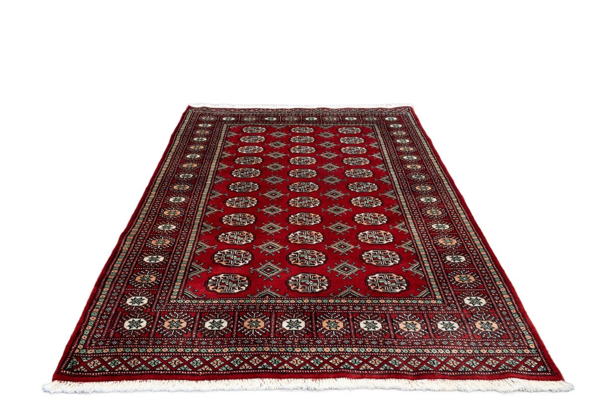 A traditional oriental rug with a deep red field, featuring a central row of circular medallions, a patterned border, and white fringe on the ends, shown against a plain white background.