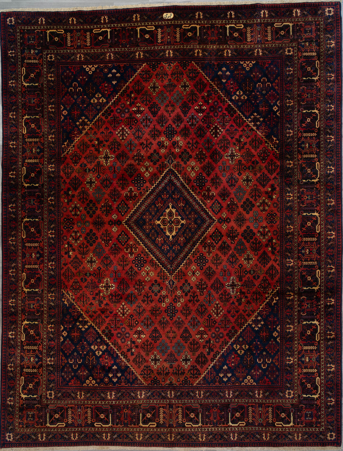 Red and navy handknotted wool Persian Joshagan rug with a diamond lattice medallion pattern and woven weaver's signature, 10' x 13'.